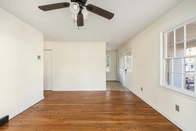 an empty room with wooden floor closet and windows