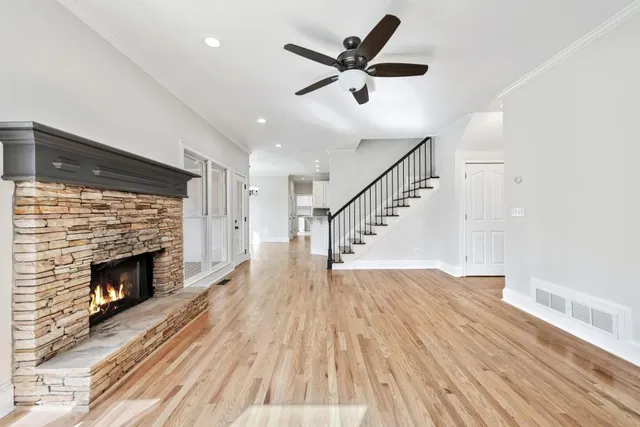 an empty room with wooden floor fan and windows