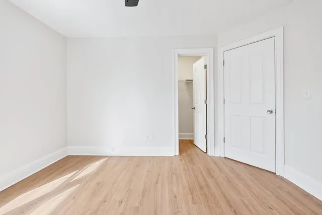 a view of an empty room with window and wooden floor