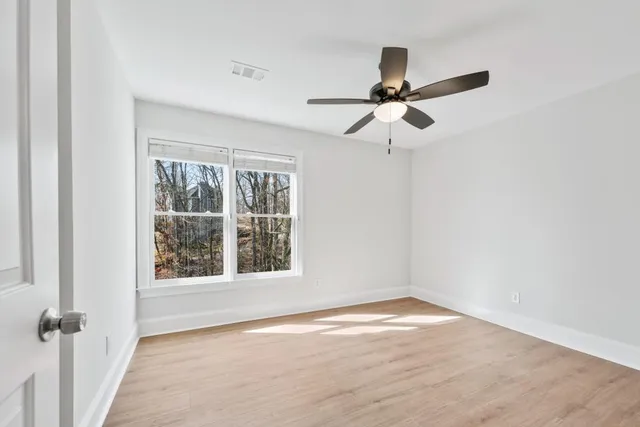 an empty room with wooden floor and windows