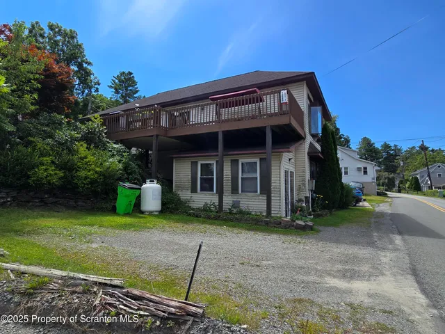 a view of a house with a yard plants and large tree