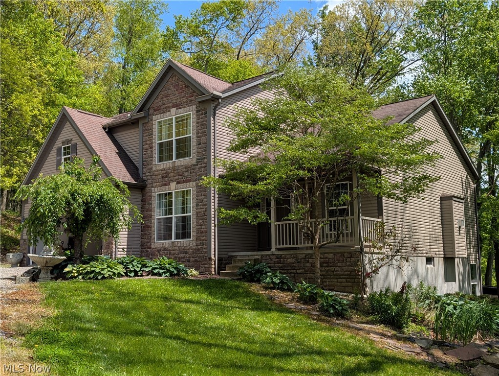 11154 Johnsford Road Southwest Beach City, OH 44608 - Photo 1 of 50 Two-story residence featuring a stone and siding facade, a covered porch with white railings, and a prominent gable roofline