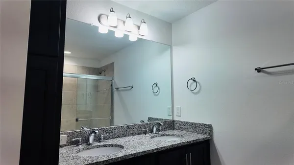 a bathroom with a granite countertop sink a light fixture and a mirror
