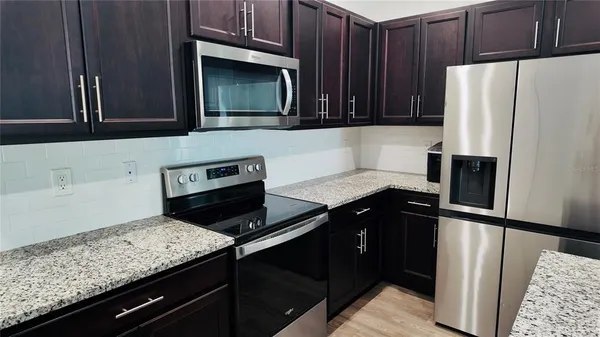 a kitchen with granite countertop stainless steel appliances and wooden cabinets