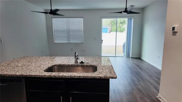 a kitchen with granite countertop kitchen island a sink appliances and a window