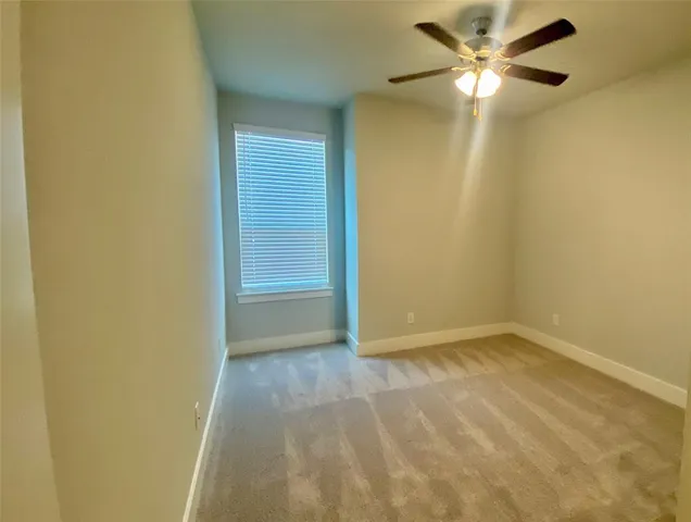 an empty room with a ceiling fan and a window