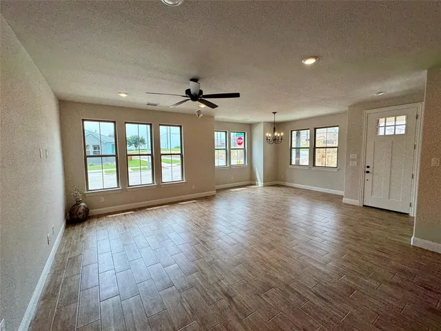 a view of an empty room with window and wooden floor