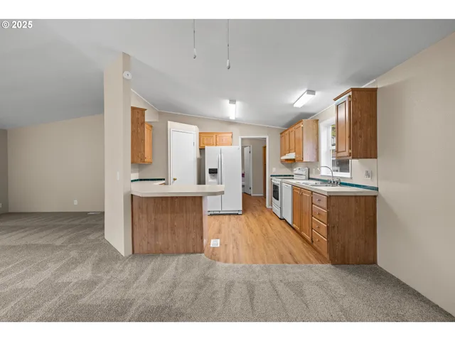 a large kitchen with kitchen island a sink dishwasher stove and white cabinets with wooden floor