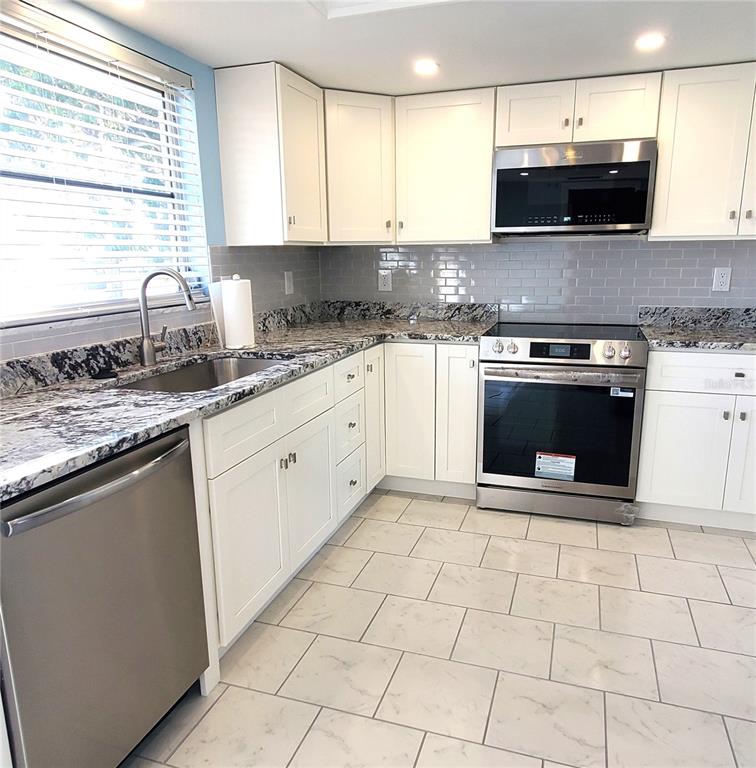 531 Neponsit Drive Venice, FL 34293 - Photo 11 of 37 a kitchen with stainless steel appliances granite countertop a stove a sink and a microwave