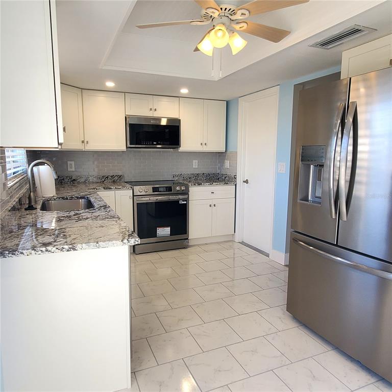 531 Neponsit Drive Venice, FL 34293 - Photo 10 of 37 a kitchen with stainless steel appliances granite countertop a refrigerator a stove a sink and a microwave