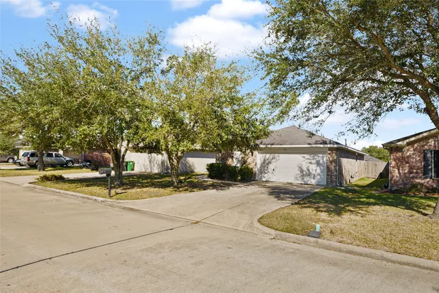 a view of a house with a yard and large tree