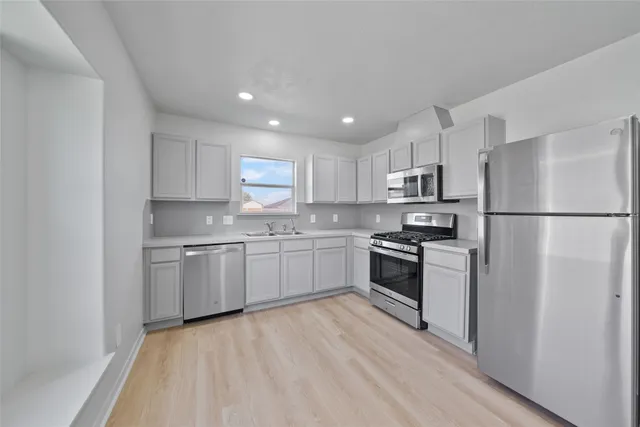 a kitchen with a refrigerator a stove top oven and white cabinets