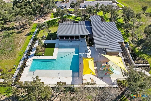 an aerial view of a house with swimming pool and large trees