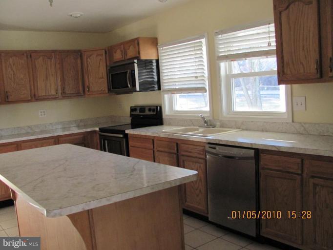 7609 Bull Run Road Manassas, VA 20111 - Photo 6 of 15 a kitchen with a stove a sink a microwave a dining table and chairs