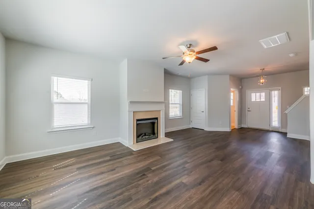 an empty room with windows fireplace and a kitchen view