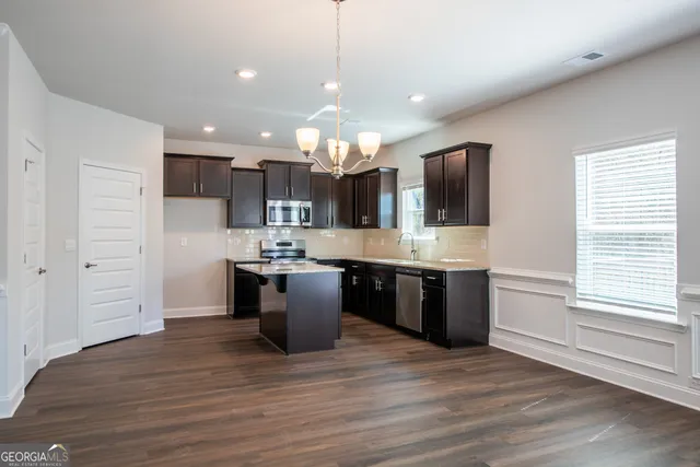 a large kitchen with a large counter top space a sink stainless steel appliances and cabinets