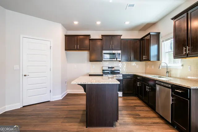 a large kitchen with stainless steel appliances wooden floors and wooden cabinets