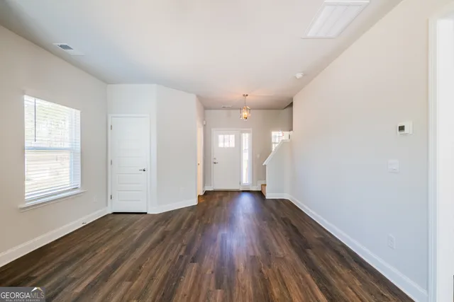 a view of an empty room with wooden floor and windows