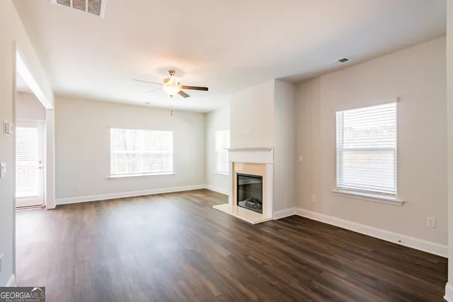 an empty room with wooden floor fireplace and windows