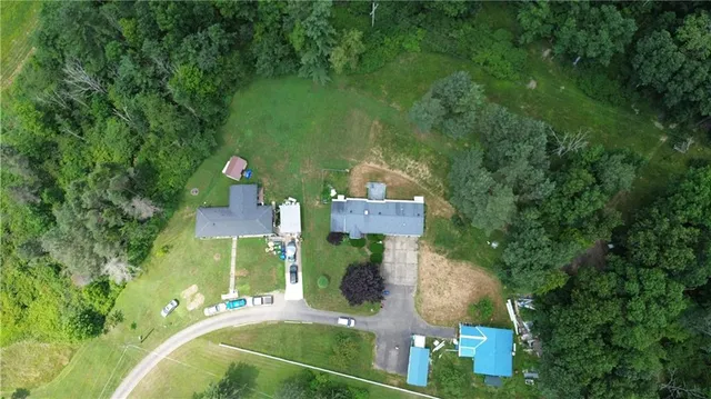 an aerial view of a house with a yard swimming pool and trees
