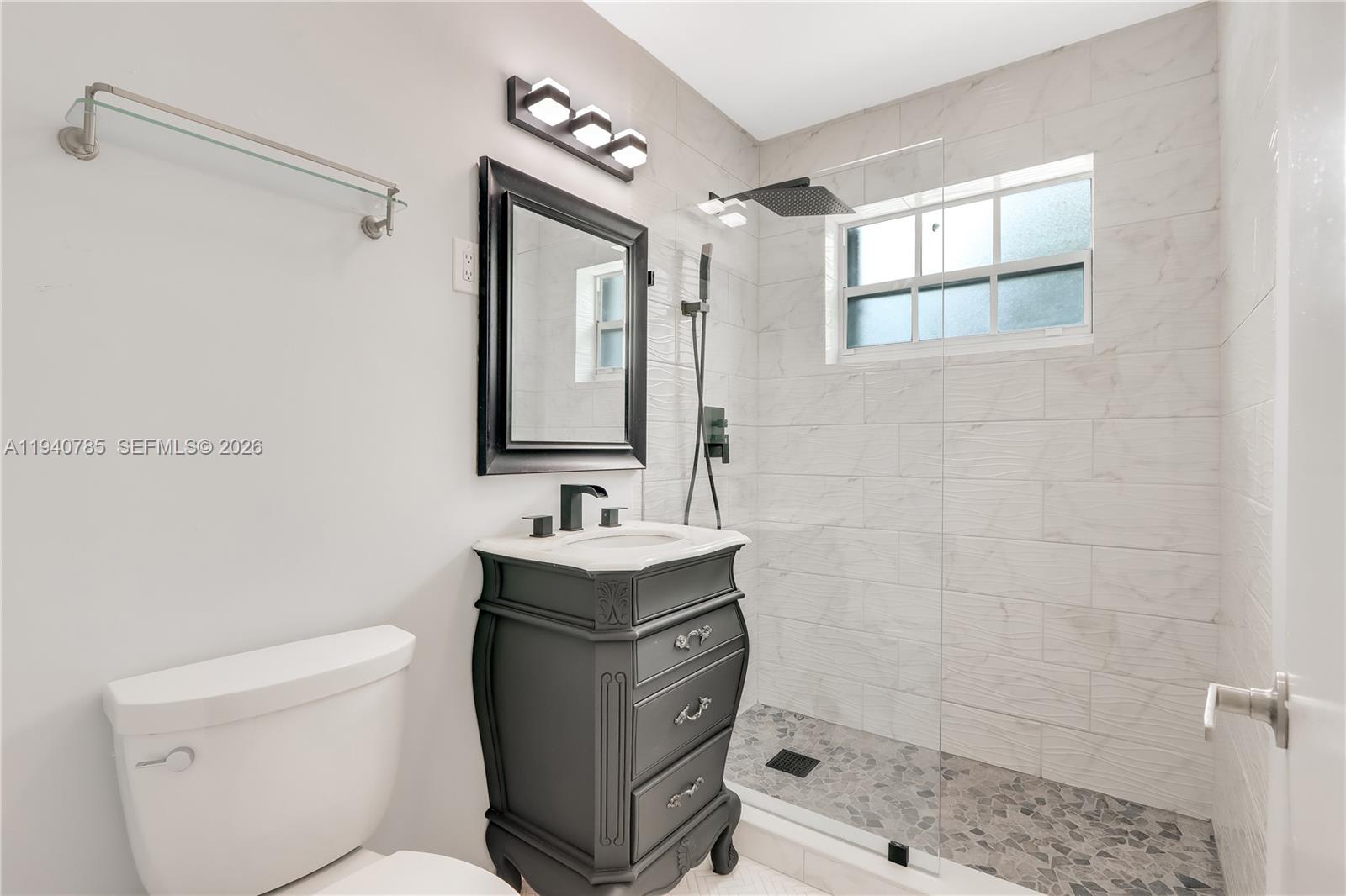 5725 Southwest 107th Place Miami, FL 33173 - Photo 14 of 21 a bathroom with a toilet a sink a mirror a shower and vanity