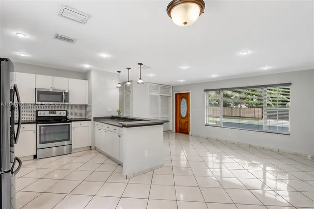 a kitchen with granite countertop a stove a sink a window and stainless steel appliances