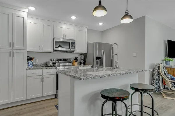 a kitchen with stainless steel appliances granite countertop a stove a sink and a refrigerator with wooden floor