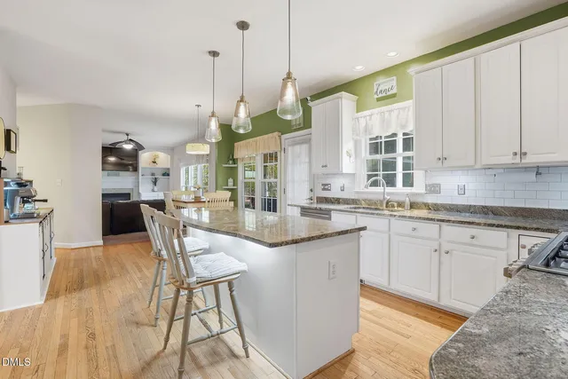 a kitchen with granite countertop a stove a sink a dining table and chairs