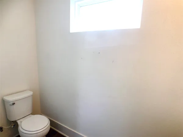 a white toilet sitting next to a white wall
