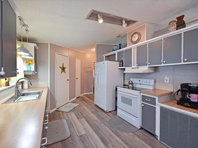a kitchen with a refrigerator wooden floor and a stove top oven