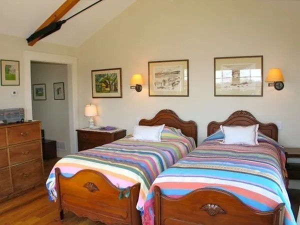 a bedroom with two beds and painting on the wall