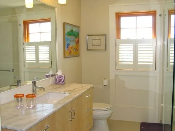 a bathroom with a granite countertop sink toilet and next to a window