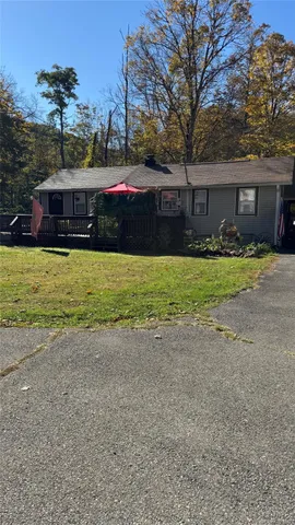 a view of small white house with a yard and garage
