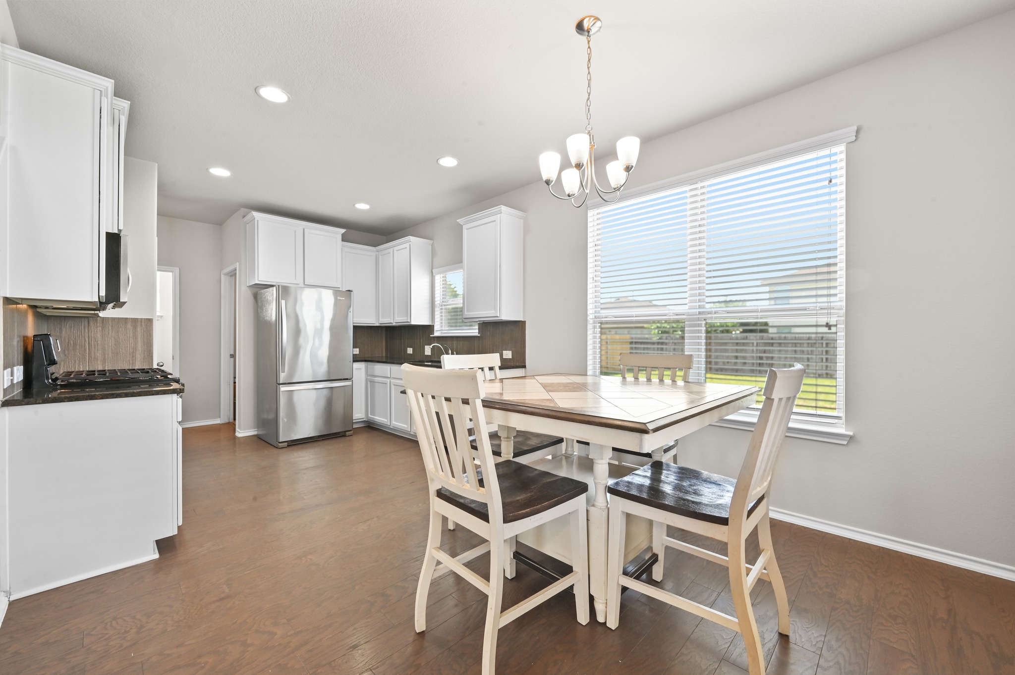 209 Noddy Road Buda, TX 78610 - Photo 8 of 30 Kitchen and dining area featuring wood-finish flooring, white cabinetry, dark countertops, and recessed lighting