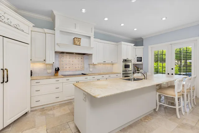 a kitchen with a sink a stove a refrigerator and white cabinets