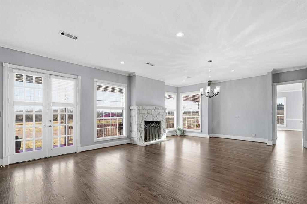 707 Cullins Road Rockwall, TX 75032 - Photo 9 of 40 an empty room with wooden floor fireplace and windows