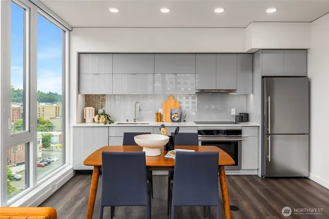 a kitchen with stainless steel appliances granite countertop a stove a refrigerator a sink a dining table and chairs with wooden floor