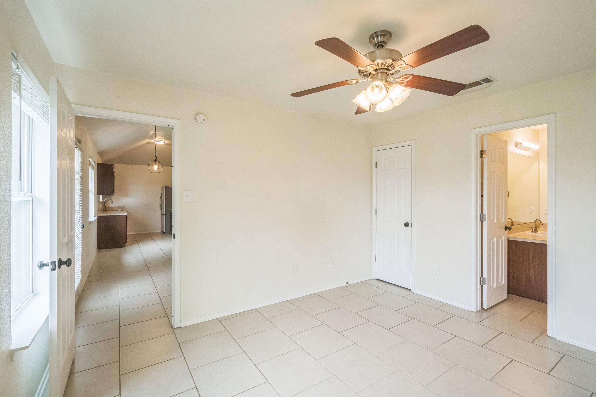 224 Amber Lane Jarrell, TX 76537 - Photo 13 of 16 Unfurnished bedroom featuring light tile patterned flooring, ceiling fan, and ensuite bathroom