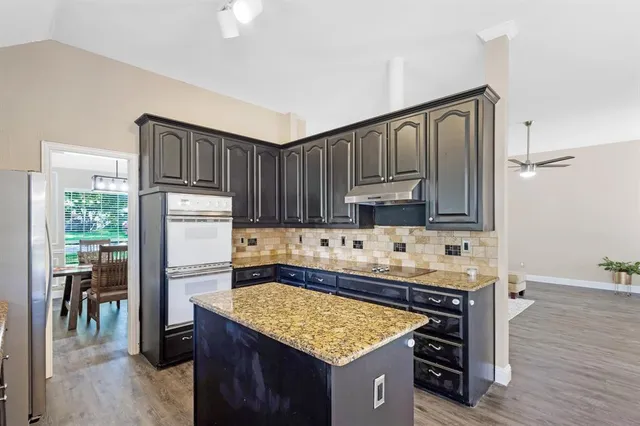 a kitchen with kitchen island granite countertop a sink stove and refrigerator