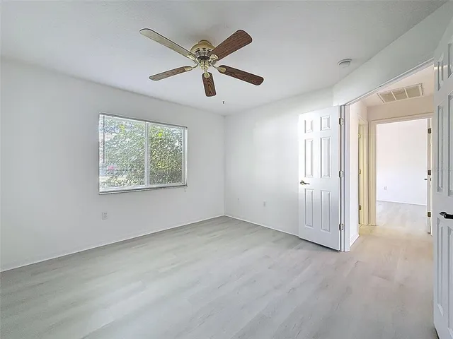 an empty room with a window and a fan