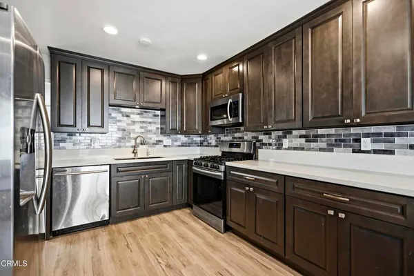 a kitchen with stainless steel appliances granite countertop a refrigerator a sink and wooden cabinets