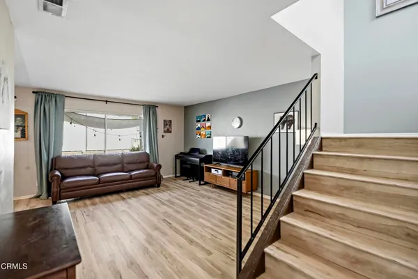 a living room with furniture and kitchen view with wooden floor