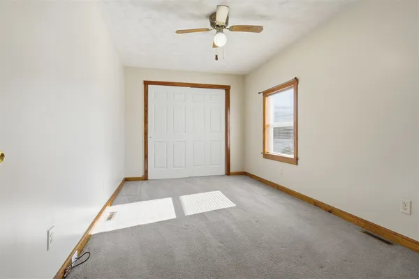 an empty room with windows and fan