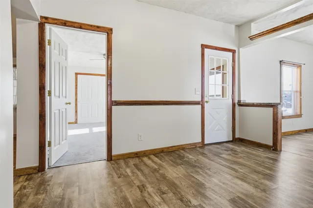 an empty room with wooden floor and a kitchen