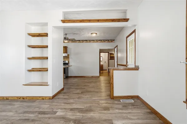 a view of empty room with wooden floor and fan