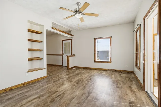 a view of empty room with wooden floor and fan
