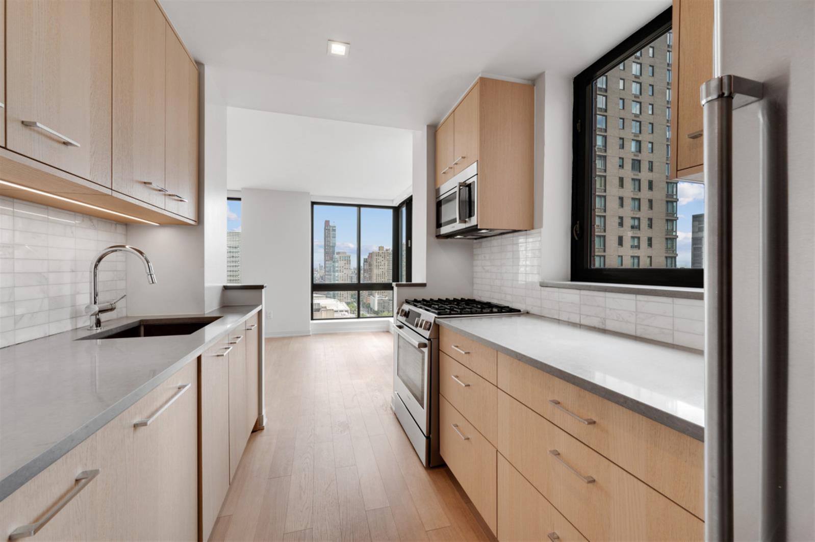 1 Columbus Place, Unit N31B Manhattan, NY 10019 - Photo 6 of 8 a kitchen with granite countertop a sink stove and cabinets