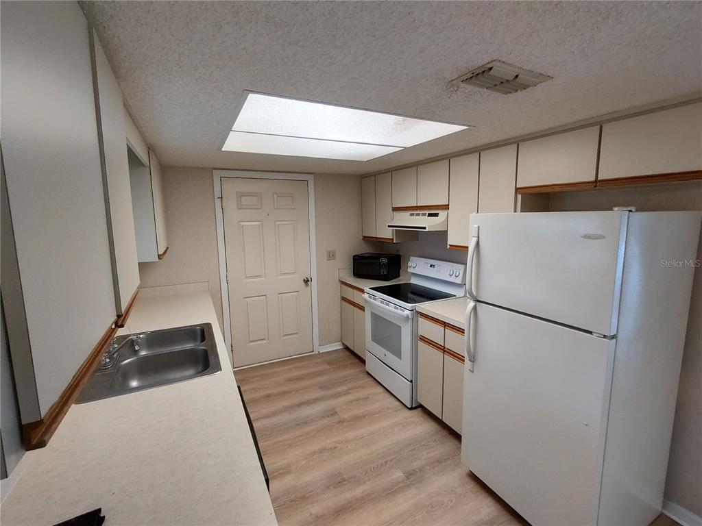 6345 Southwest 115th Street Road Ocala, FL 34476 - Photo 5 of 10 a kitchen with a refrigerator a stove top oven and cabinets
