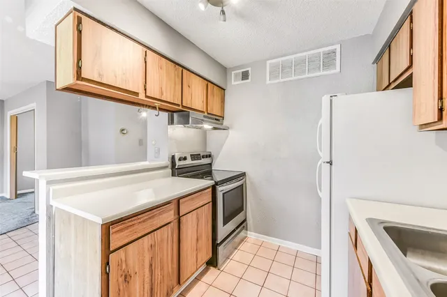 a kitchen with stainless steel appliances granite countertop a refrigerator a stove and a sink with cabinets
