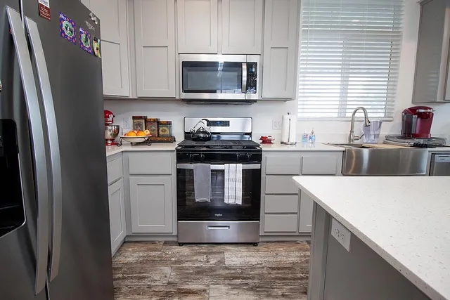 a kitchen with stainless steel appliances granite countertop a stove a sink and a refrigerator